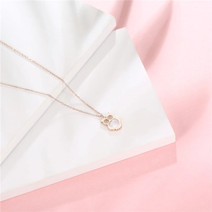 Detailed view of rose gold owl pendant necklace with diamond accent on white stairs
