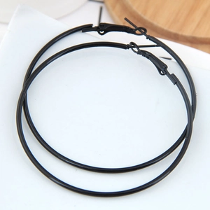 Detailed view of large black matte hoop earrings with a secure clasp on a white surface