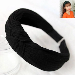 Detail of black ribbed knit knotted headband featuring a stylish cross twist design