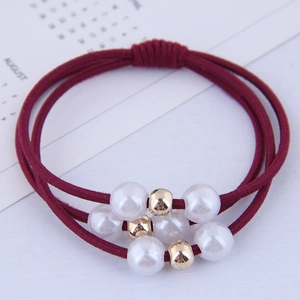 Three-strand burgundy elastic hair tie with white pearls and gold beads on a calendar