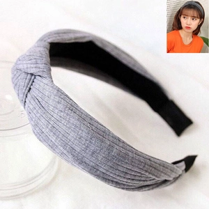 Detail of grey knitted twist knot headband showing textured fabric on a female model