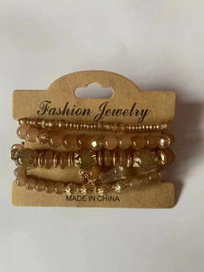 Detail of four-piece bohemian beaded bracelet set in champagne gold and amber tones