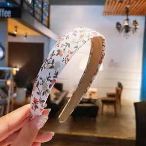 Floral print headband with sweet orange and pink blossoms on a cream fabric base