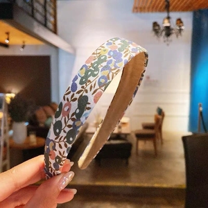 Floral print headband with non-slip lining in a warm indoor cafe setting for women