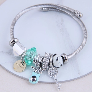 Silver beaded charm bracelet with heart, deer head and key pendants on marble surface