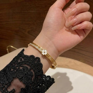 Elegant gold titanium steel cuff bracelet with sparkling white floral charm and diamonds