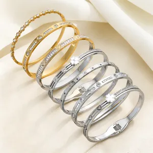 Detail of stacked titanium steel bracelets with clover and heart motifs on satin cloth