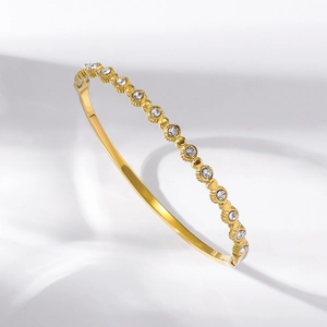 Detailed macro view of gold-tone titanium steel bracelet with sparkling white zircons