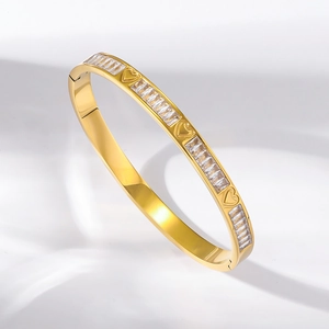 Macro detail of gold titanium steel bangle with rectangular zircons and heart shapes
