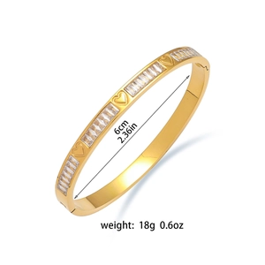 Gold titanium steel heart bangle with cubic zirconia and dimension details on white background