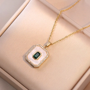 Macro de un collar dorado con gema verde corte esmeralda y detalles en nácar fino