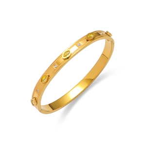 Détail du bracelet rigide en acier titane doré orné de pierres jaunes et cristaux