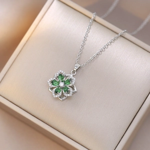Detail of silver flower pendant necklace with green drop-shaped petals and zircons