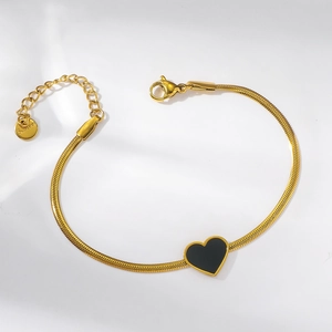 Detailed macro view of gold snake chain bracelet with black heart charm and S.Steel tag