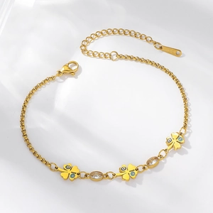 Détail du bracelet doré avec trèfles à quatre feuilles, œil bleu et cristaux clairs