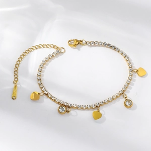 Detail of a gold titanium bracelet featuring polished heart charms and clear zircon stones