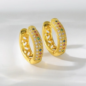 Detalle de pendientes de aro dorados con circonitas de colores y diseño calado