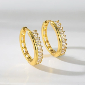 Detalle de pendientes de aro dorados con circonitas corte baguette y diseño de ranura hueca