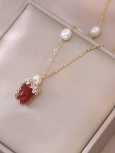 Détail du collier avec pendentif agate rouge et perles sur une chaîne dorée en acier titane