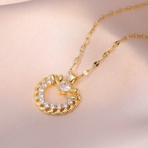 Collier avec pendentif coeur doré orné de zircons et d'un nœud sur anneau torsadé