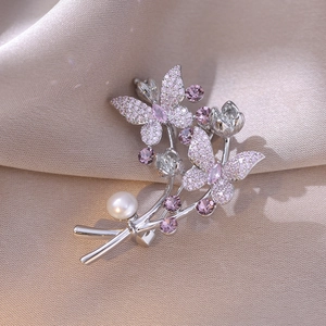 Details einer Feder-Blumen-Brosche mit lila Zirkonia und weißer Perle auf Seide