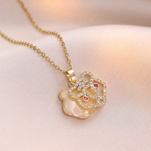 Collier doré avec pendentif fleur en émail blanc et pierres précieuses rouges