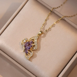 Dettaglio macro del ciondolo a farfalla dorato con cristalli viola e accenti in zircone