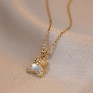 Gouden beer ketting met parelmoer hanger en strikje op zachte satijnen stof