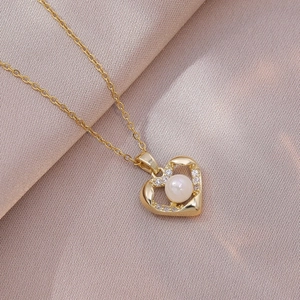 Collar de corazón dorado con perla blanca y cristales sobre tela de seda rosa