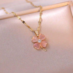 Pink heart clover necklace with gold chain and crystals on elegant champagne satin fabric