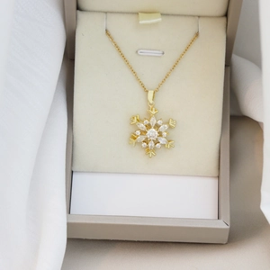 Elegante goldfarbene Schneeflocken-Halskette mit Zirkonia auf weißem Seidenhintergrund