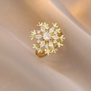 Exquisite gold snowflake ring with clear zircon crystals on champagne silk background