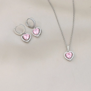 Detalle macro de un conjunto de collar y pendientes de corazón rosa en plata halo