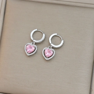 Detalle de pendientes de corazón rosa con micro-pavé de cristales en metal plateado