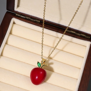 Chic gold chain necklace featuring a glossy red apple pendant with green gemstone leaf
