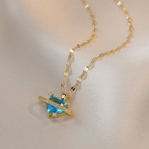 Collier doré avec pendentif cœur en zircon bleu sur un tissu élégant en soie champagne