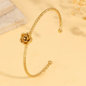 Detail of gold rose flower cuff bangle featuring intricate diamond-cut textured metal
