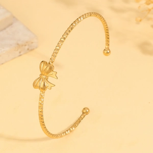 Elegant gold titanium steel open bangle featuring a 3D bow design and textured finish