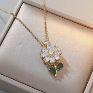 Detailopname van gouden bloemenketting met fonkelende witte kristallen en groene bladeren