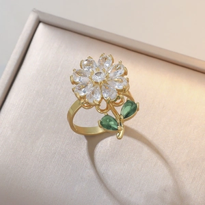 Elegante gouden bloemring met kristallen bloemblaadjes en groene edelsteenblaadjes