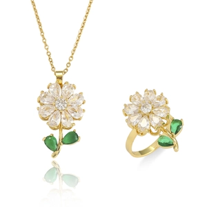 Detail van gouden bloemen sieradenset met witte zirkonia en groene edelsteen accenten