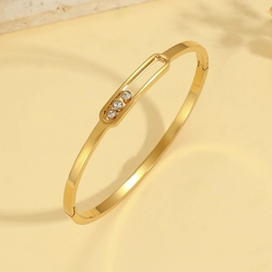 Brazalete de acero de titanio dorado con tres piedras de circonita cúbica deslizantes