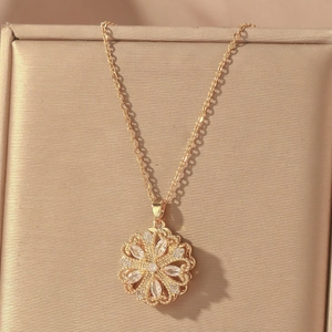 Close-up of golden hollow flower pendant necklace with white crystals on gold silk