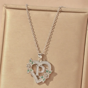 Detail of silver heart pendant with letter P, green stones and sparkling cubic zirconia