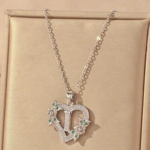 Macro view of heart-shaped letter L pendant with zircon flowers on champagne velvet
