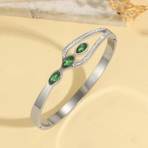 Titanium steel bangle with green marquise gems and white zircons on a marble base