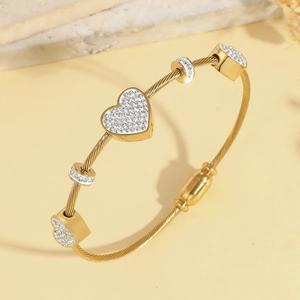 Dettaglio del bracciale a cavo dorato con ciondoli a cuore e cristalli scintillanti