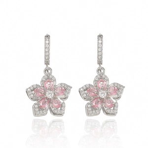 Detail of pink zircon flower earrings with silver micro-pave setting on white surface
