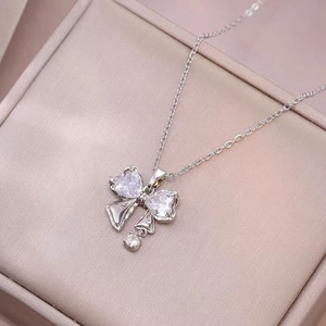 Silver bow necklace featuring heart-shaped zircons in a pink satin jewelry gift box