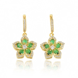 Détail de boucles d'oreilles fleur avec pierres vertes et pavé de zircons dorés